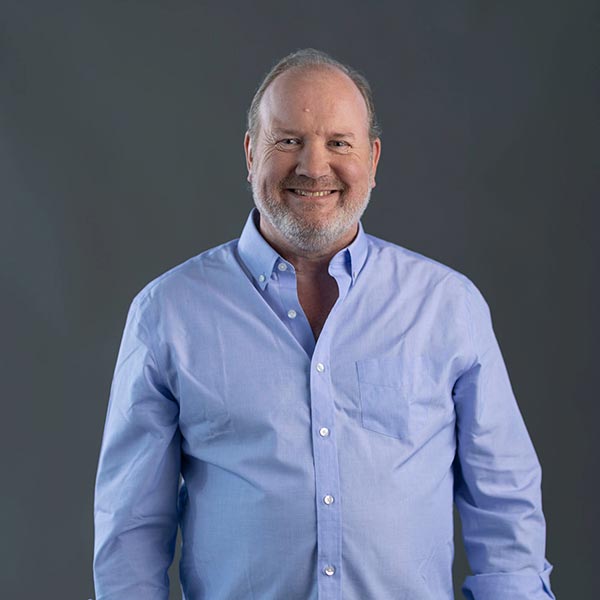 Portrait of a smiling man Bernard Kreilmann, CEO, wearing a blue shirt who has a silver beard.