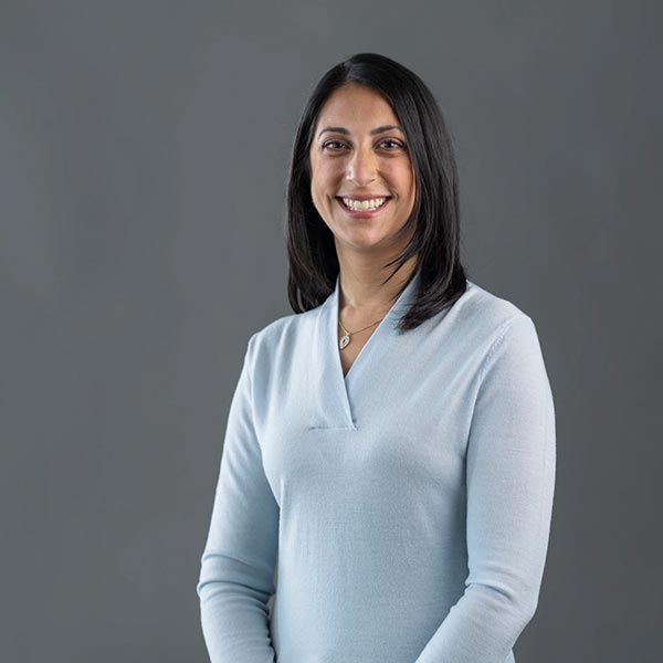 Portrait of a smiling woman Mala Wiedemann, VP Marketing, with dark mid-length hair wearing a baby blue sweater and smiling for the camera.