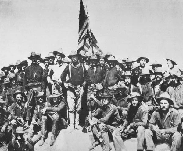 Group of Rough Riders (men with an American flag) gather during the Spanish American war in 1898. 