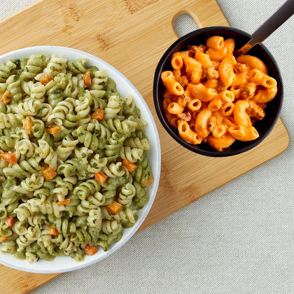 Overhead view of a bowl of Suddenly Salad pasta salad on the left and a pan of noodle Helper on the right. 